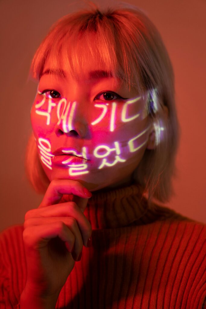 Woman's face illuminated by colorful neon light projection, creating vibrant artistic effect.