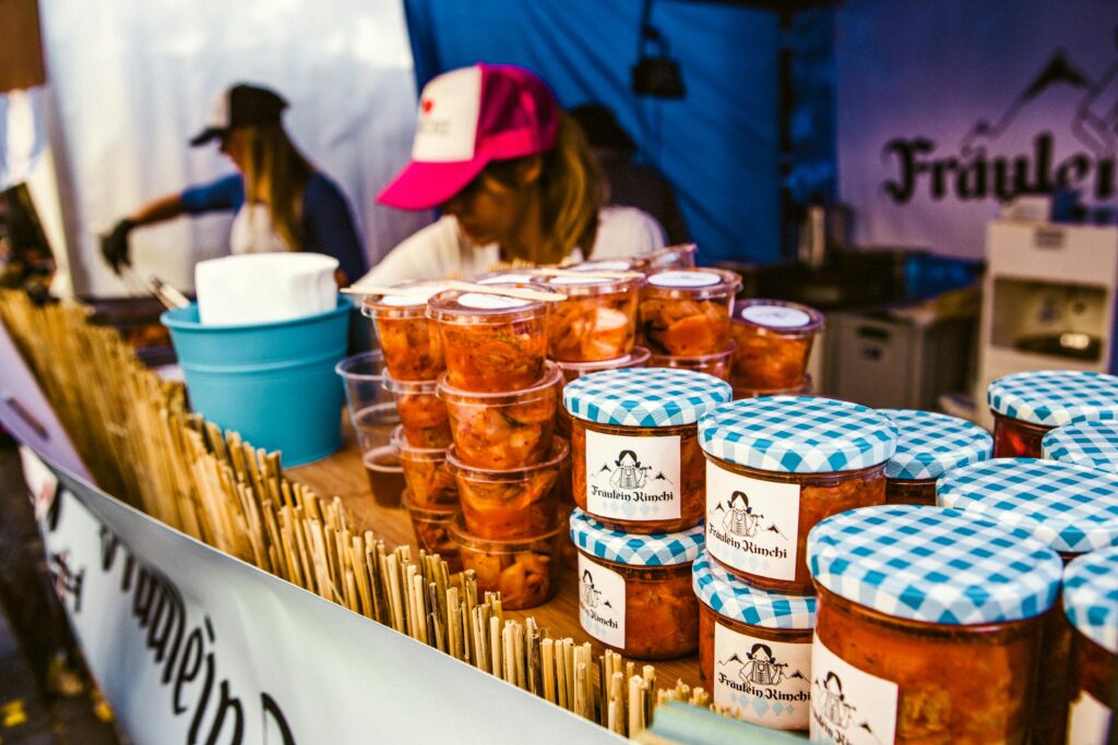 Colorful jars of kimchi at Berlin street market stall with sellers.