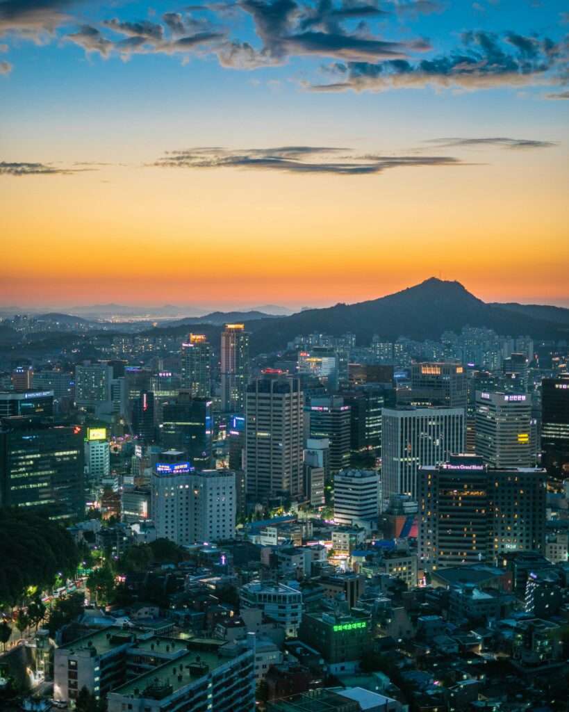 Stunning twilight view of Seoul's skyline featuring skyscrapers and mountains.