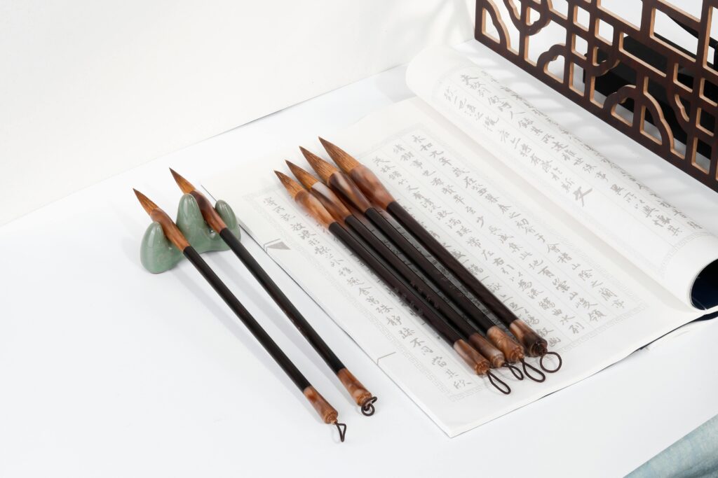 A close-up of traditional calligraphy tools and paper featuring ink brushes and Asian script.