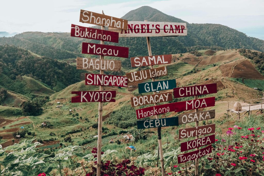 Vibrant signpost with global city names set against Digos City's lush green hills.