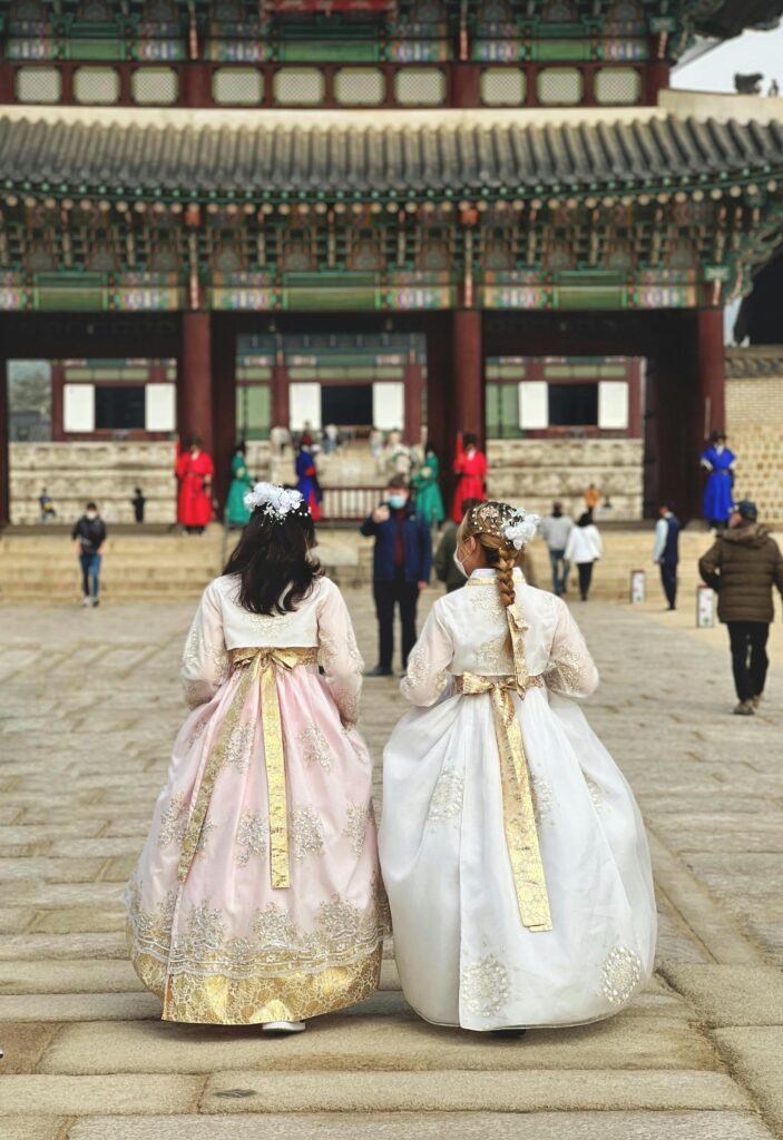 Two women in hanbok walking at Gyeongbokgung Palace, Seoul.